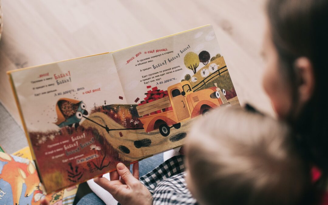 top down view of a child with blonde hair looking at a children's book that is open.